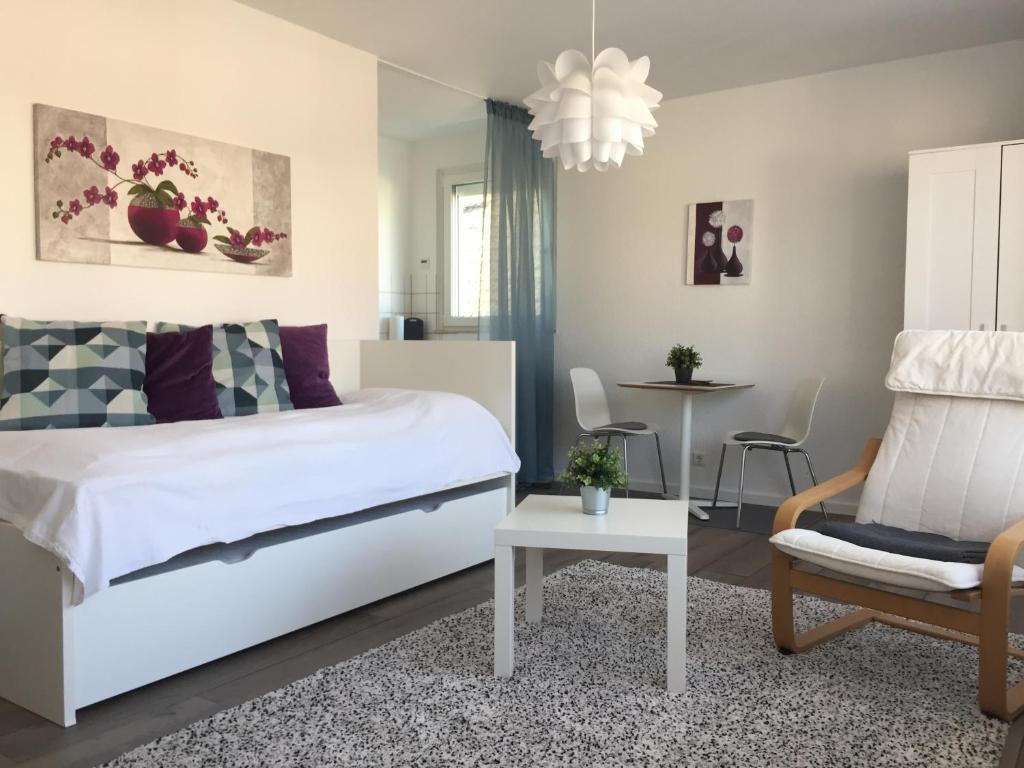 ein Schlafzimmer mit einem weißen Bett und einem Stuhl in der Unterkunft Appartement Ratingen Tiefenbroich in Ratingen