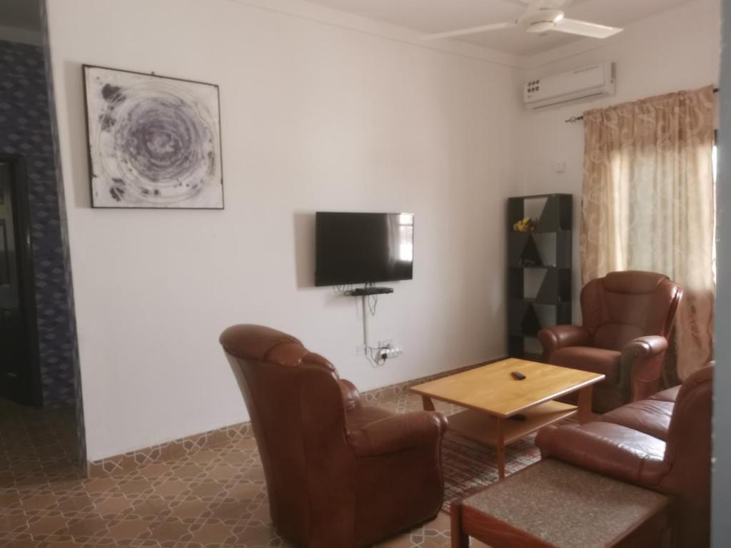 a living room with leather chairs and a table and a tv at BARAKAH ESTATE APARTMENTS in Sere Kunda