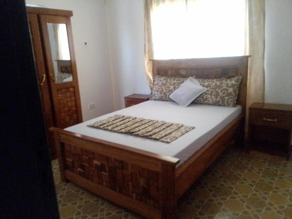 a bedroom with a wooden bed with a window at BARAKAH ESTATE APARTMENTS in Sere Kunda