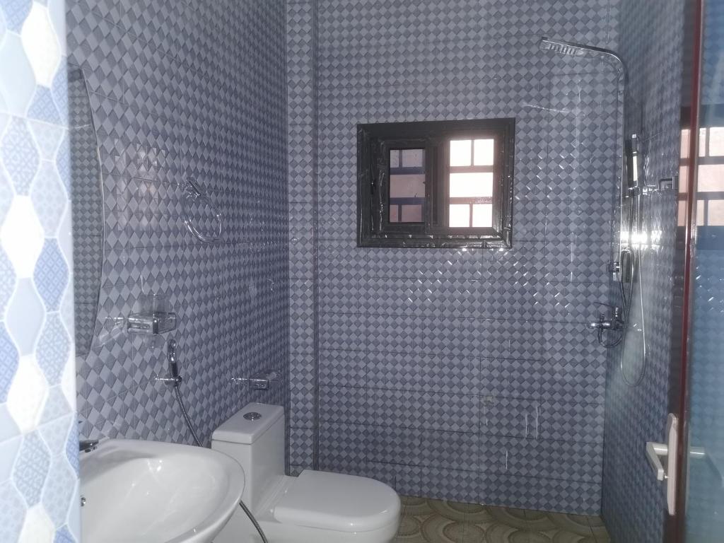 a bathroom with a toilet and a sink and a window at BARAKAH ESTATE APARTMENTS in Sere Kunda