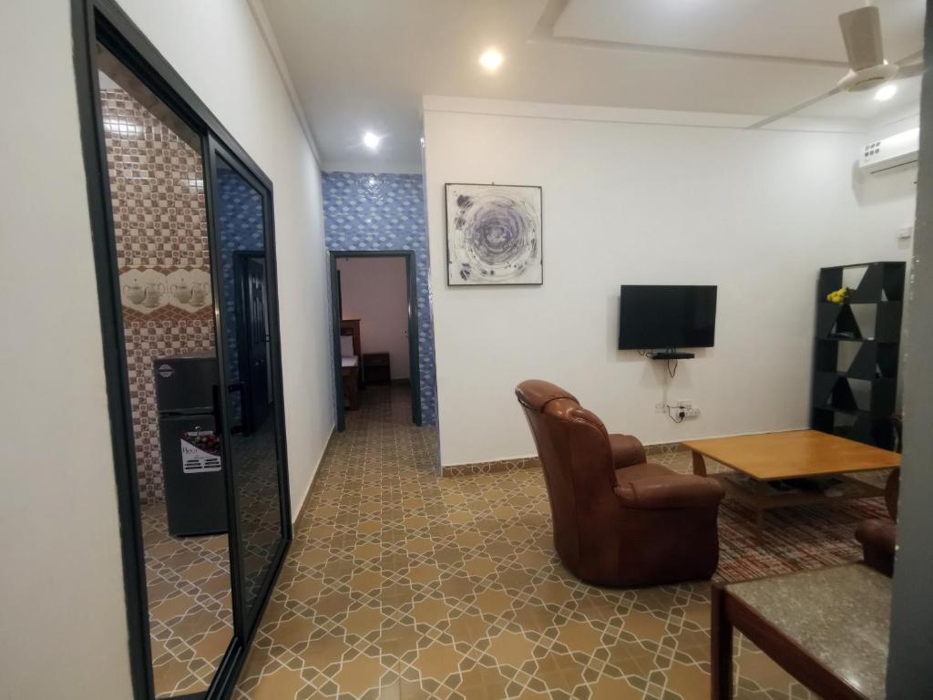 a living room with a chair and a table at BARAKAH ESTATE APARTMENTS in Sere Kunda