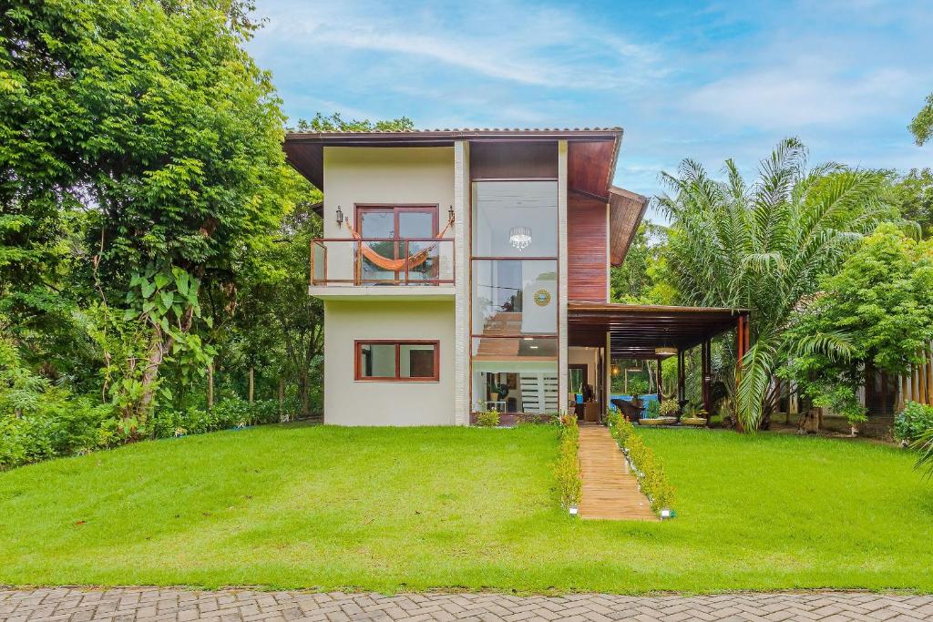 a house with a green lawn in front of it at PF26 Excelente Casa 4 Suítes - Praia do Forte in Mata de Sao Joao