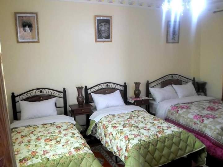 a bedroom with two beds and two pictures on the wall at Guest House Zaida in Zeïda