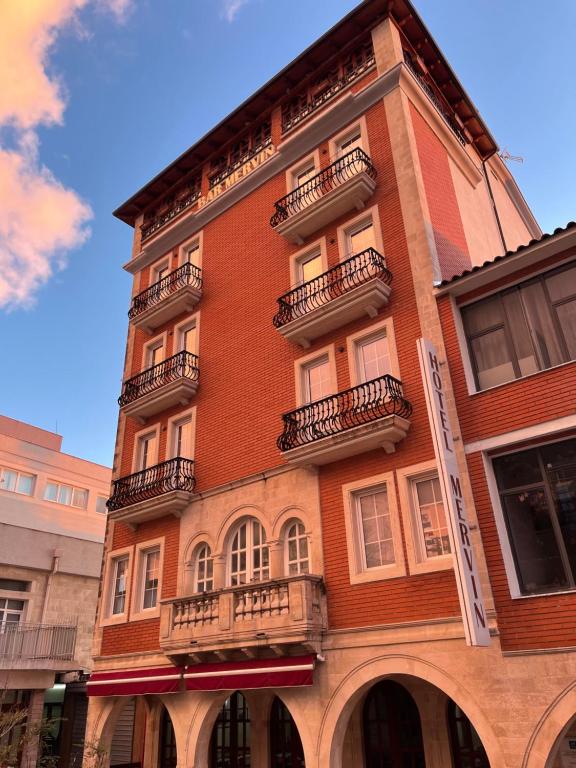 ein hohes rotes Backsteingebäude mit Balkonen darauf in der Unterkunft Mervin Hotel in Kruja