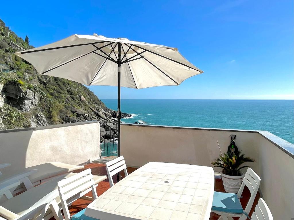a patio with a table and an umbrella and the ocean at Families or Groups 3 Terrazzi Apartment on Sea in Vernazza