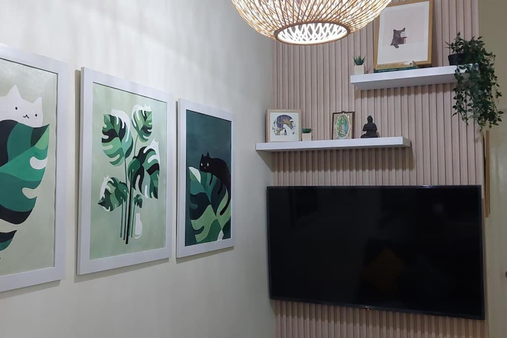 a flat screen tv on a wall with paintings at 2BR Penthouse in Brixton Place with breathtaking view of BGC in Manila
