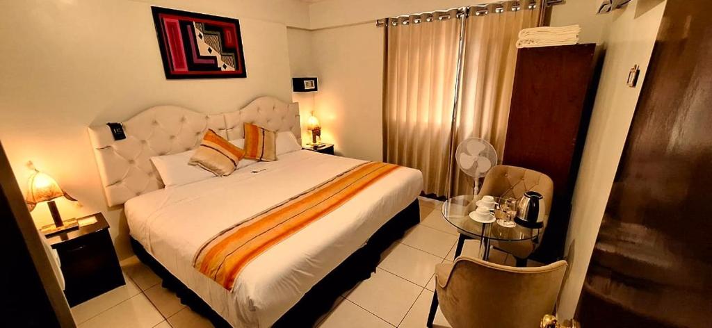 1 dormitorio con 1 cama grande y mesa de cristal en ANDINO HOTEL MACHUPICCHu, en Machu Picchu