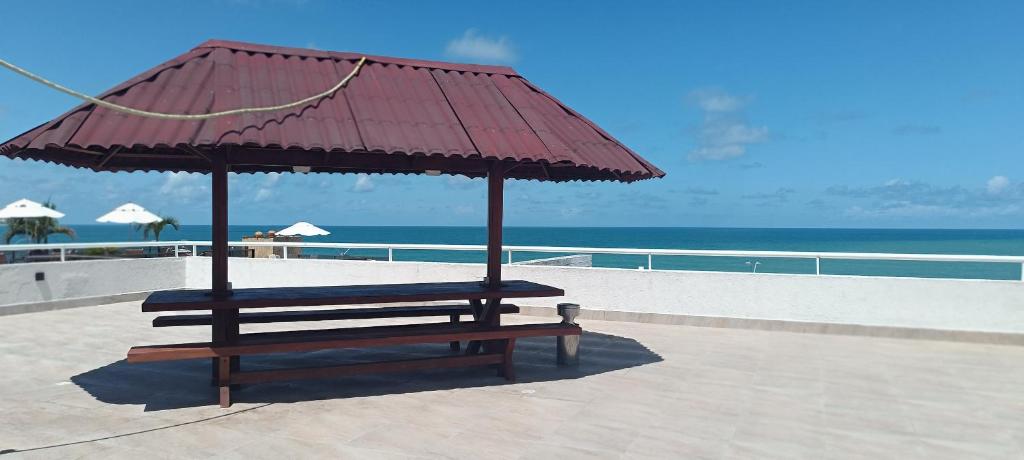 a bench with a red umbrella on the beach at Beira-Mar flat 310 Ponta Negra Beach in Natal