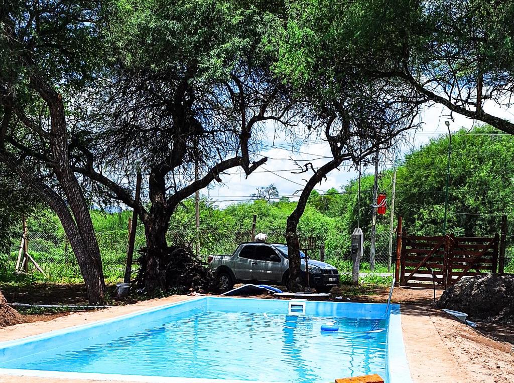 una piscina con un coche estacionado junto a un árbol en Cabaña El Forastero en Coronel Moldes