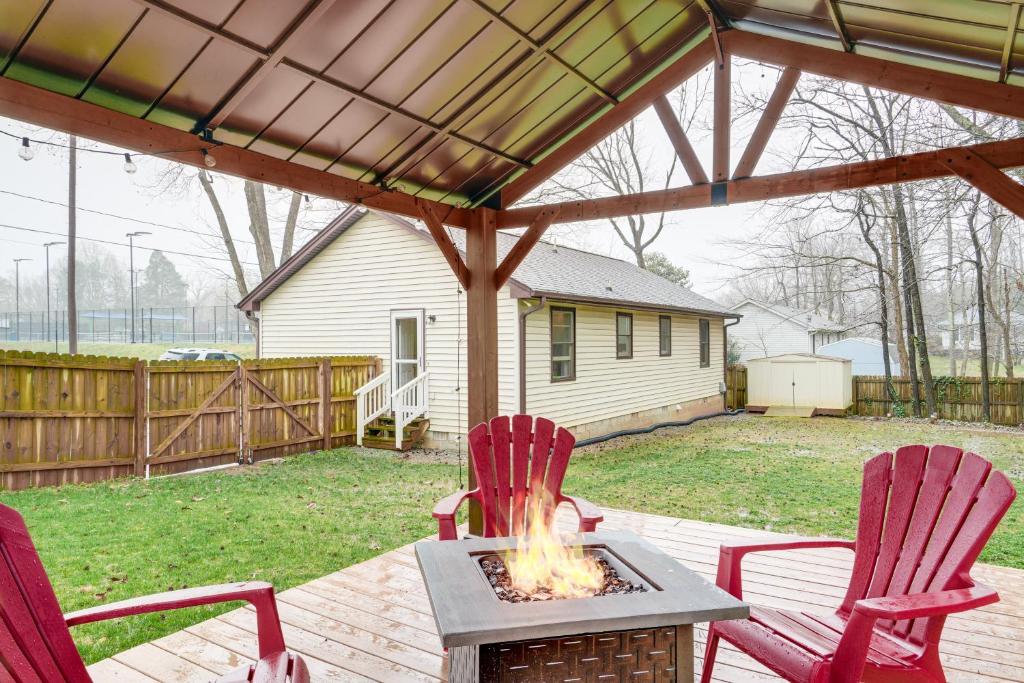 a patio with two red chairs and a fire pit at Mebane Home with Private Yard Steps to Downtown! in Mebane