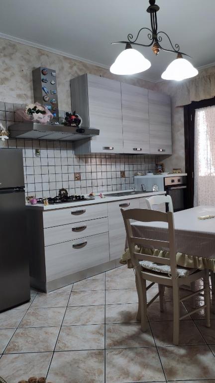 een keuken met witte kasten en een tafel en een stoel bij Casa Amici Miei in Catania