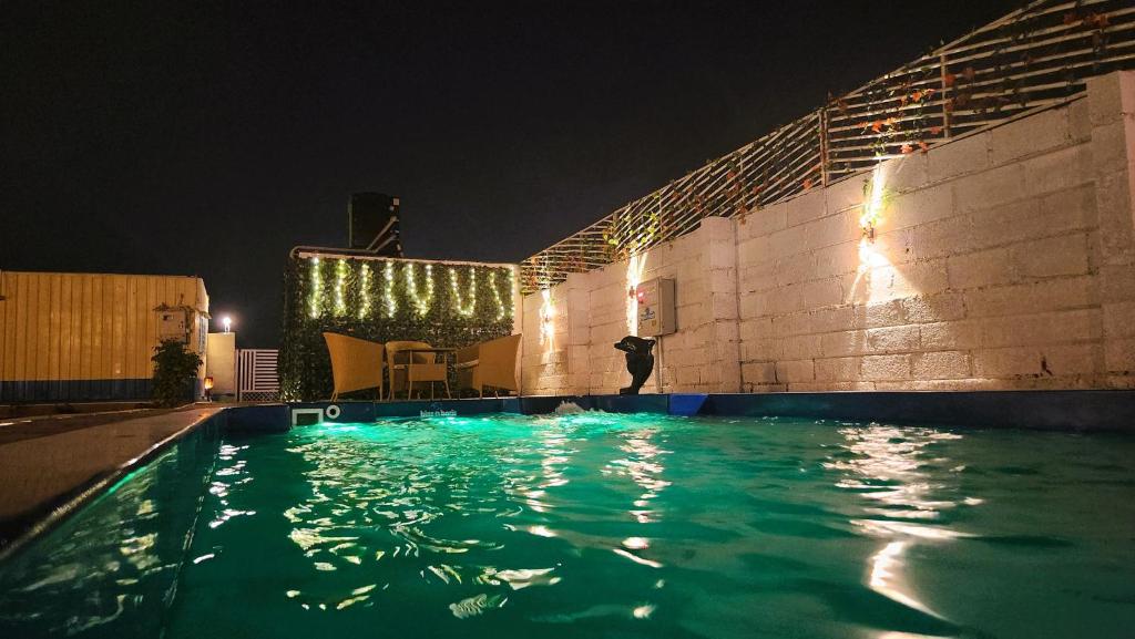 a swimming pool at night with lights on a building at Picnic for all with private heated pool & bbq in Bangalore