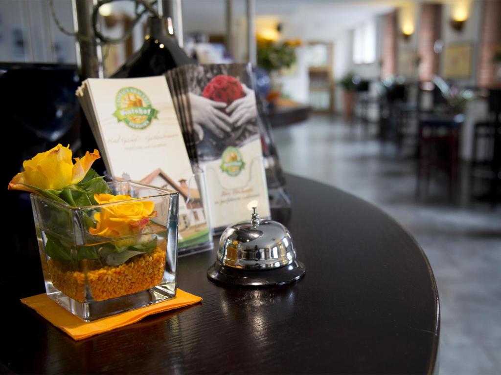 un tavolo con un vaso di fiori e una bottiglia di vino di Hotel Gutshof Herborn a Herborn