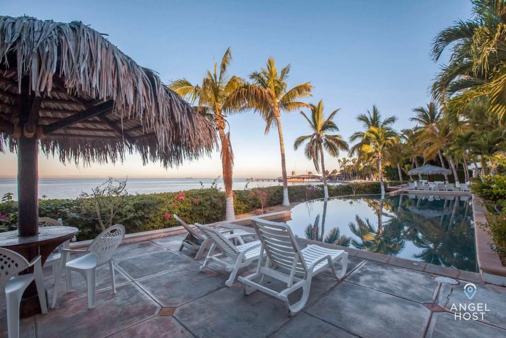 un patio con sillas, una piscina y palmeras en Private oceanview balcony & infinity pool onsite, en La Paz