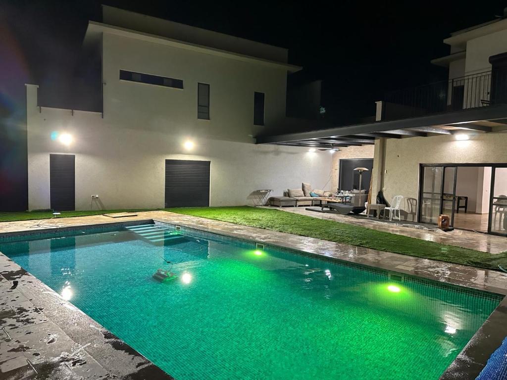 una piscina frente a una casa por la noche en בית נופש בגלבוע, en Nurit