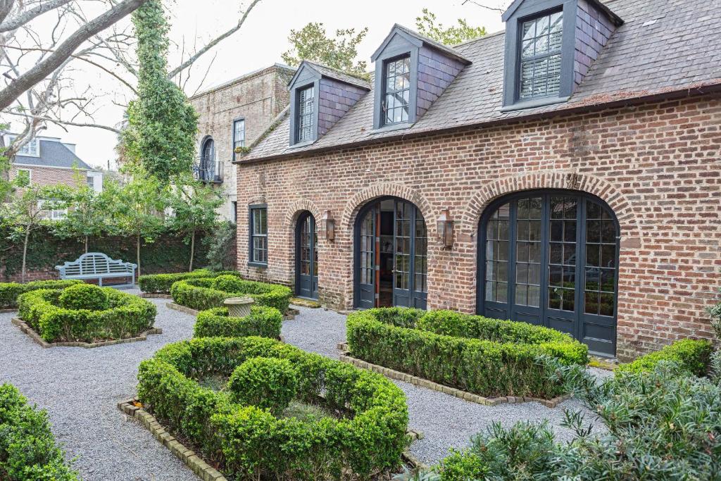 a brick house with hedges in front of it at Gibbon House at Casa Zoe in Charleston