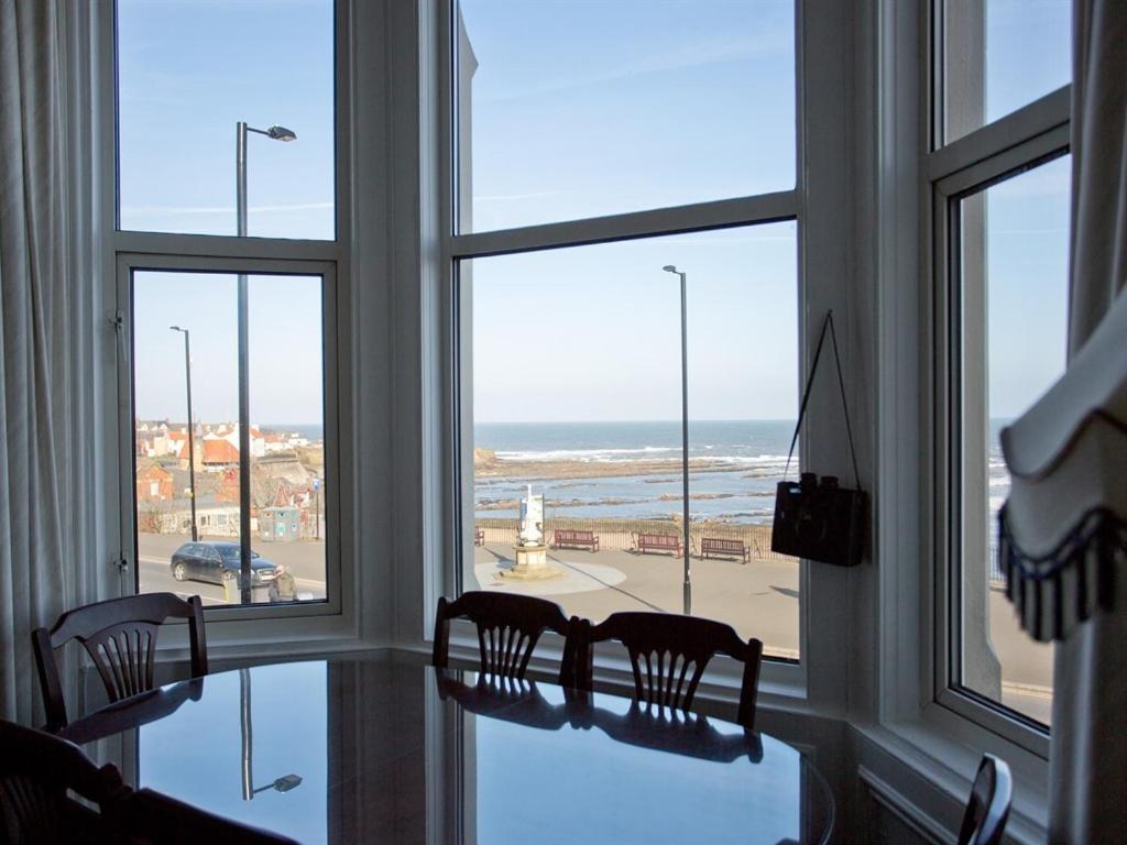 a room with a table and chairs looking out at the ocean at Seafront Apartments in North Shields