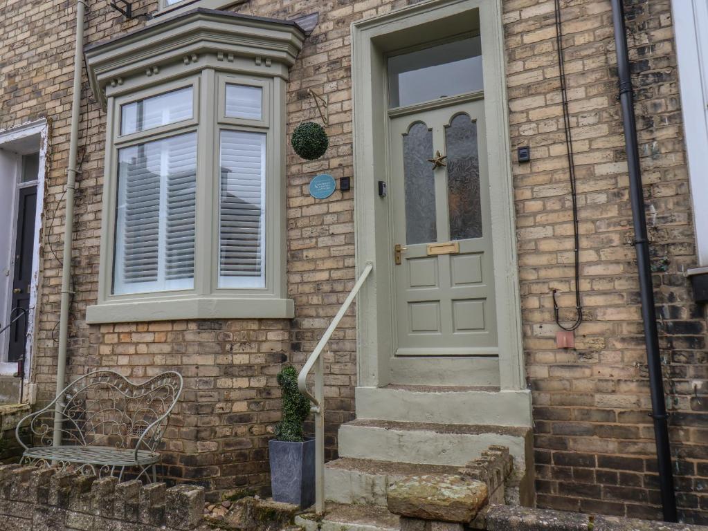 a brick house with a white door and a bench at Seastar in Whitby