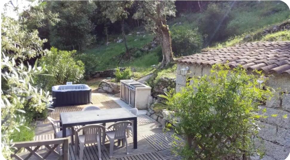 d'une terrasse avec une table, des chaises et un radiateur. dans l'établissement Gîte au coeur d'une oliveraie, à Sartène
