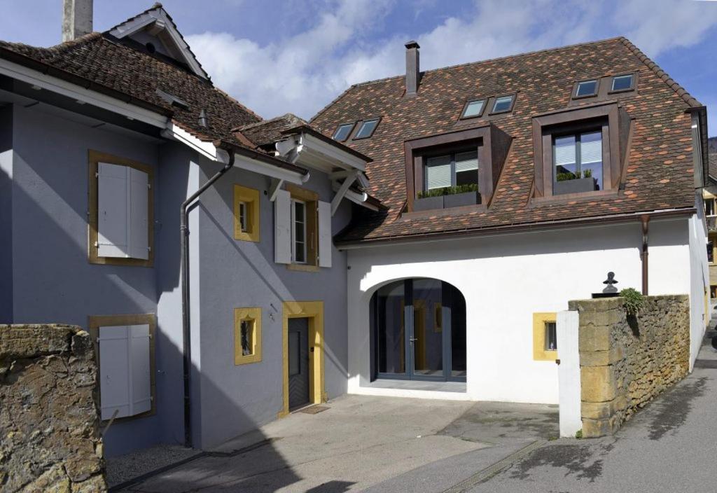 una casa bianca con porte e finestre gialle di L'Eau Forte - maison d'hôtes a Saint-Blaise