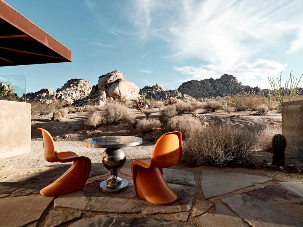 een groep oranje stoelen en een tafel in de woestijn bij Marmol Radziner's Modernist Cabin - Joshua Tree in Joshua Tree