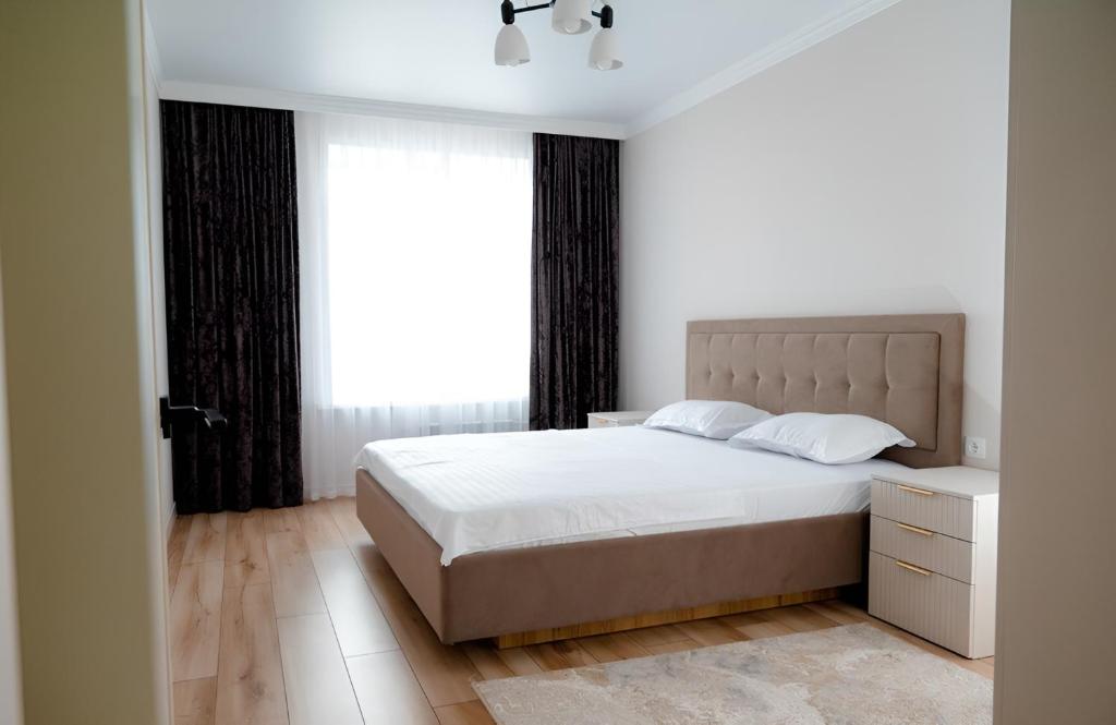 a bedroom with a bed and a large window at Новая 2х комнатная ЛЮКС квартира в центре in Kokshetau