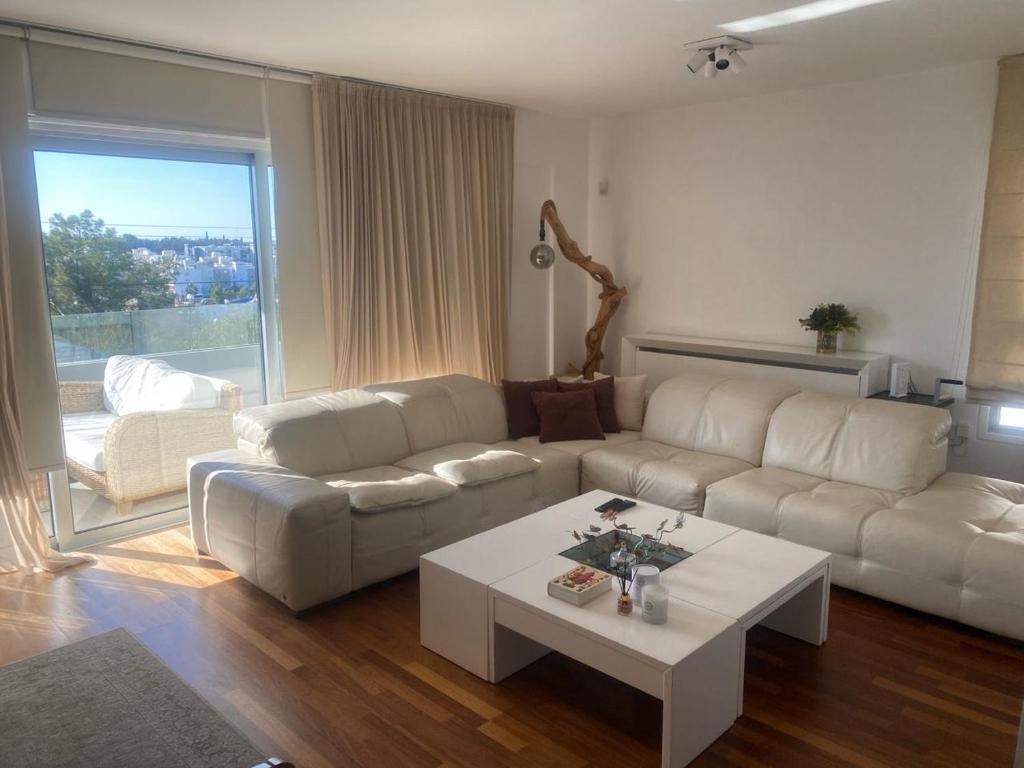 uma sala de estar com um sofá branco e uma mesa em Mont Parnasse Hill 21 em Ayios Dhometios