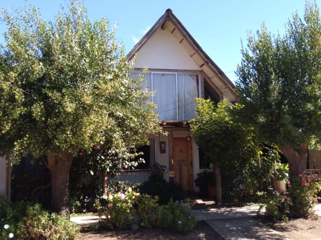 a house with trees and bushes in front of it at Cabaña Elu in Llico