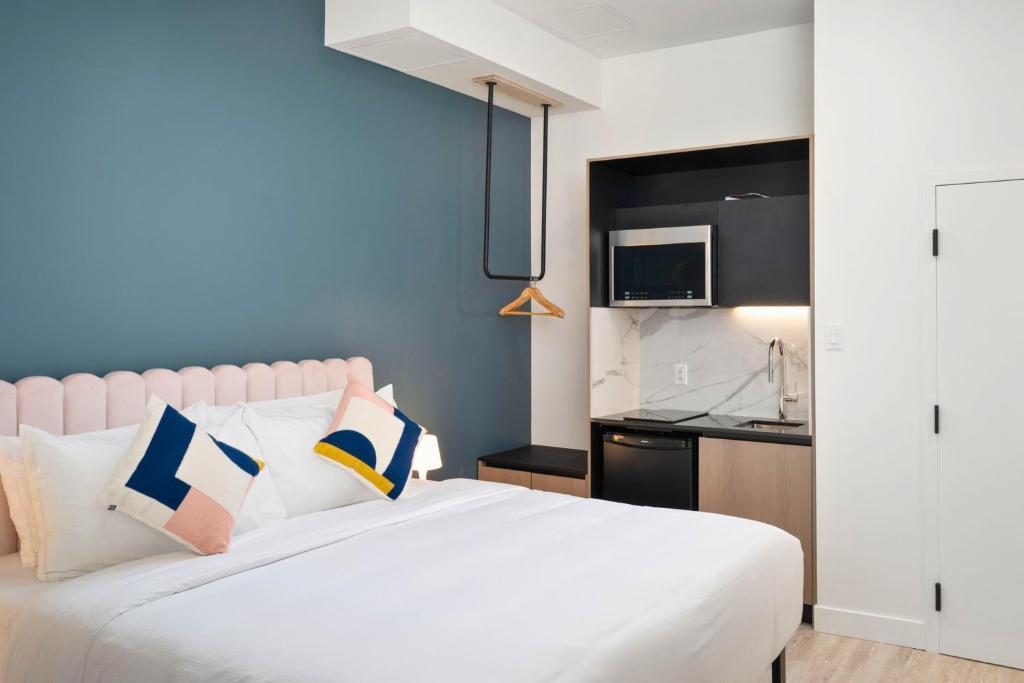 um quarto com uma cama branca com almofadas e uma cozinha em Clouds Boutique Hotel em Montreal