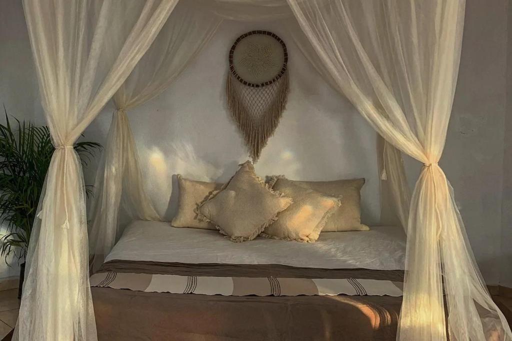 a canopy bed with white curtains and pillows at Casa Zazen in Amatlán
