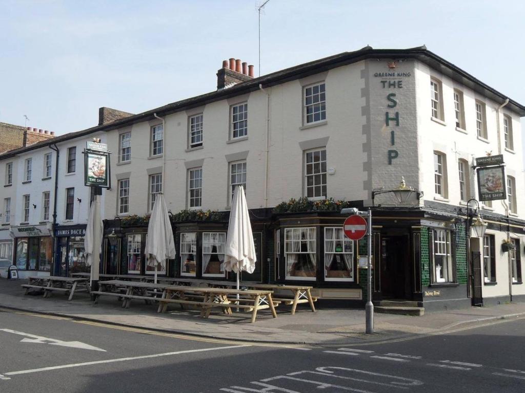 un edificio con mesas y sombrillas delante en The Ship en Chelmsford