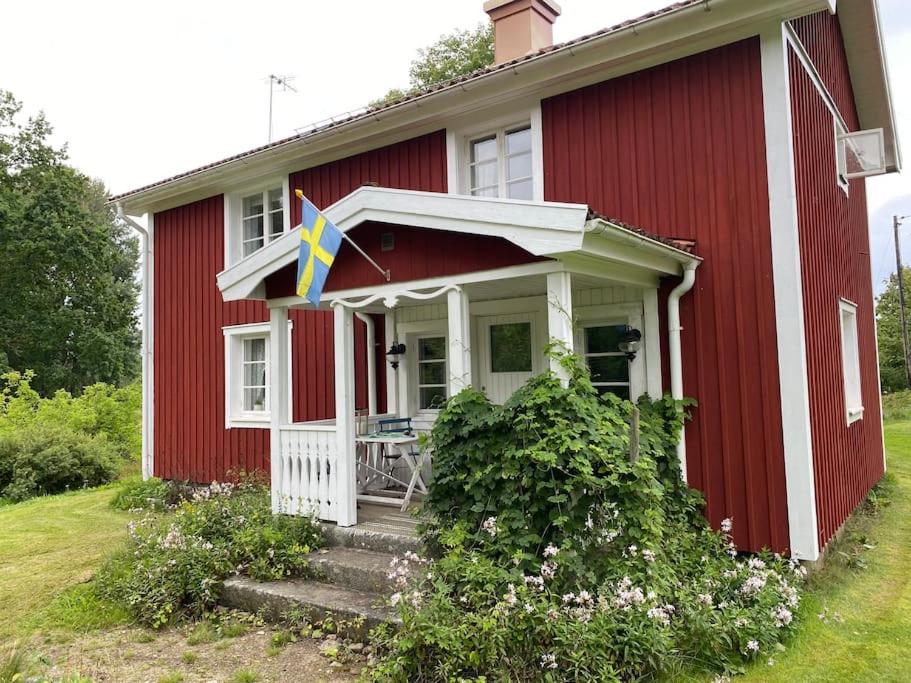 een rood-wit huis met een vlag erop bij By Lake Rusken - 2 cottages - fantastic nature in Rörvik