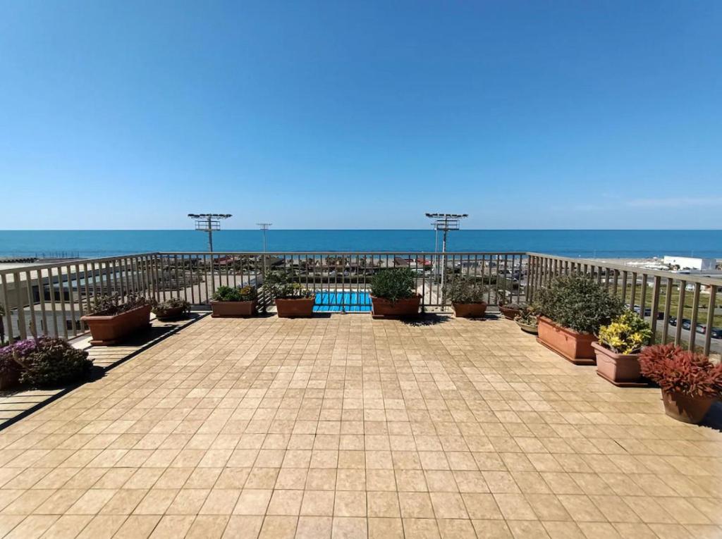 a patio with potted plants and the ocean in the background at Casa Paradiso in Lido di Ostia