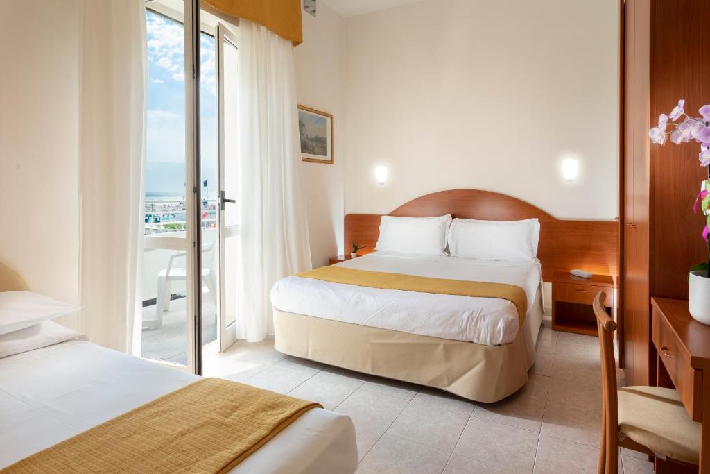 a hotel room with two beds and a balcony at Hotel Vela d'Oro in Rimini