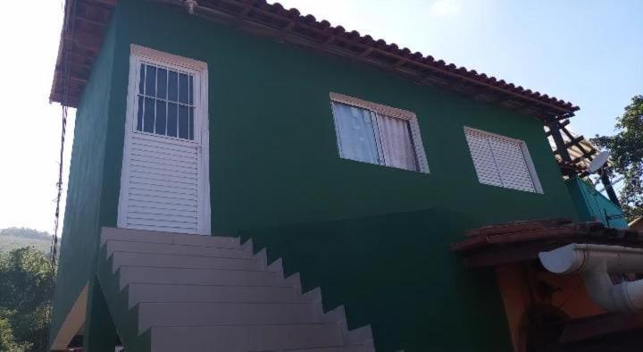 una casa verde con una escalera delante de ella en Chalé Ilhabela, en Ilhabela