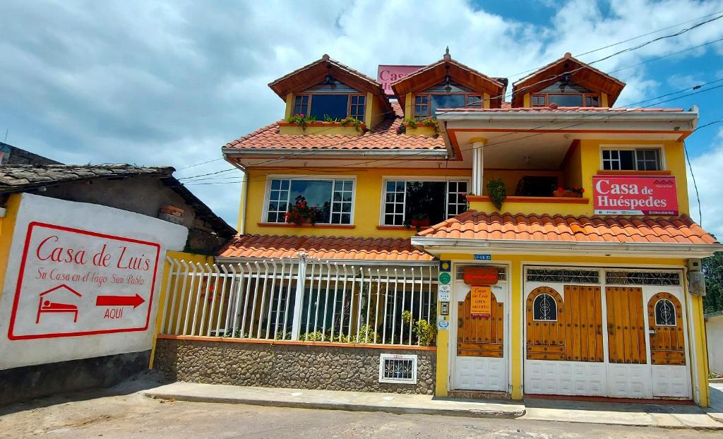 ein gelbes Haus mit einem Schild davor in der Unterkunft Casa de Luis in Otavalo