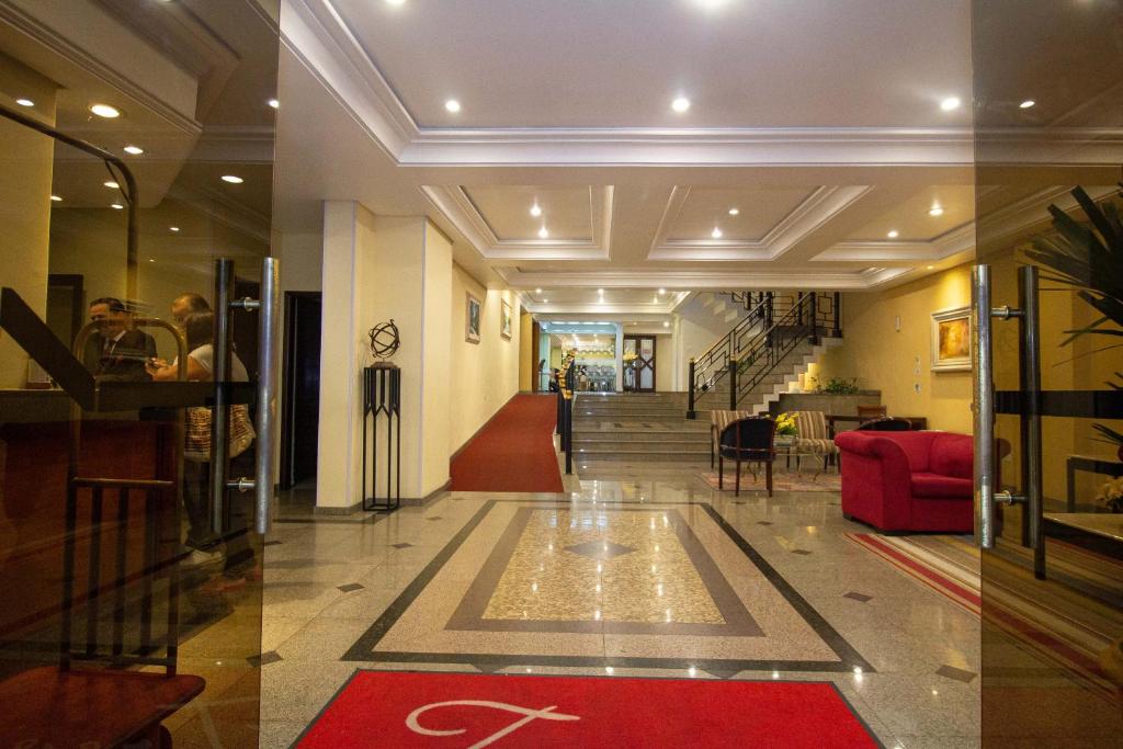 Trevi Hotel e Business في كوريتيبا: غرفة معيشة مع أريكة حمراء ودرج