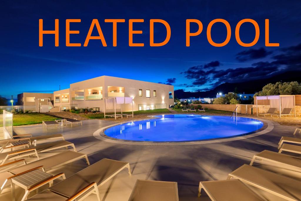 a heated pool in front of a house with lounge chairs at Belvedere Luxury Apartments & Spa in Plakias