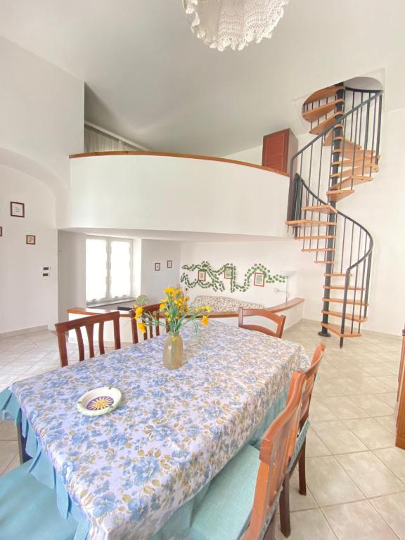 uma sala de jantar com mesa, cadeiras e escadas em Euploia Apartment em Ischia