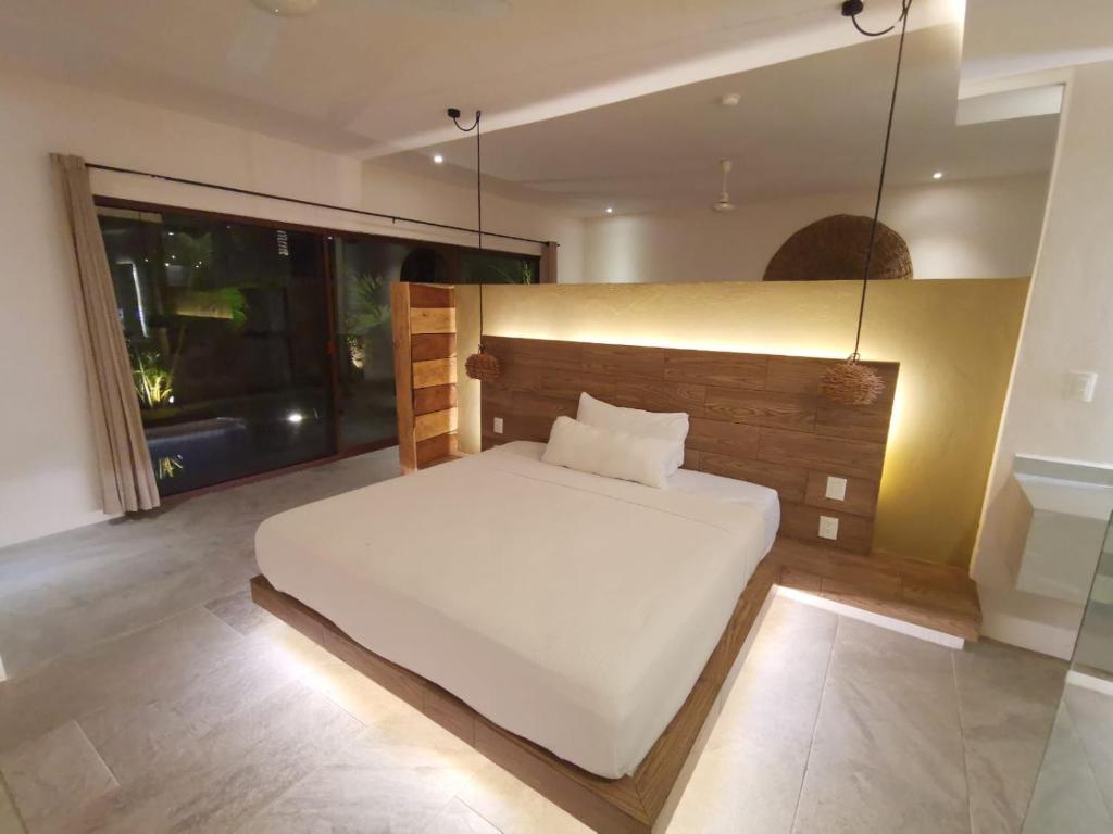 a bedroom with a white bed and a large window at Kuun Taak Tulum in Tulum