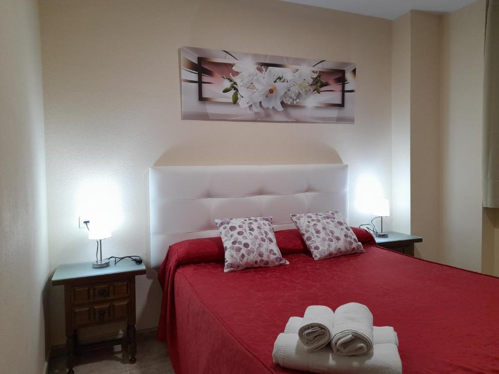 a bedroom with a red bed with two pillows at Hostal San Roque in Guadalajara