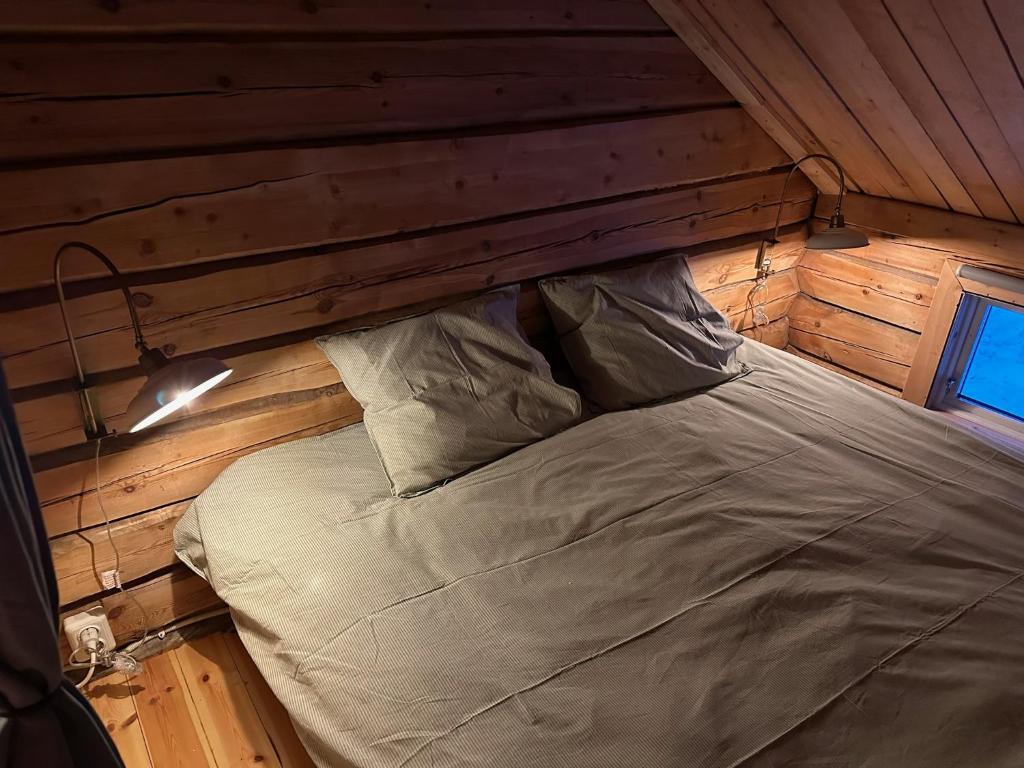 a bed in a room with a wooden wall at Cabin in the Woods in Malung