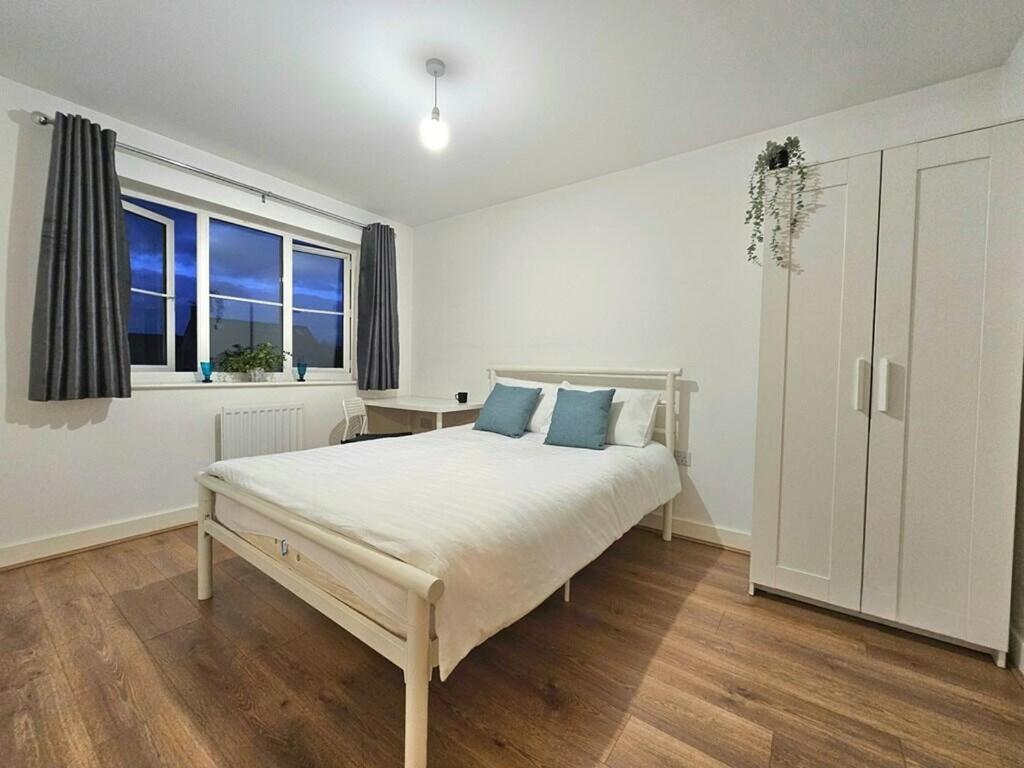 a white bedroom with a bed and a window at Modern & Fully Furnished in Bristol