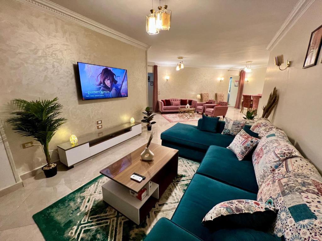 Una sala de estar con un sofá azul y un televisor. en Modern 2BR Apartment in Maadi, en El Cairo