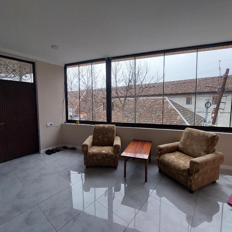 - un salon avec deux chaises, une table et de grandes fenêtres dans l'établissement Sheki Villa for big families, à Shaki