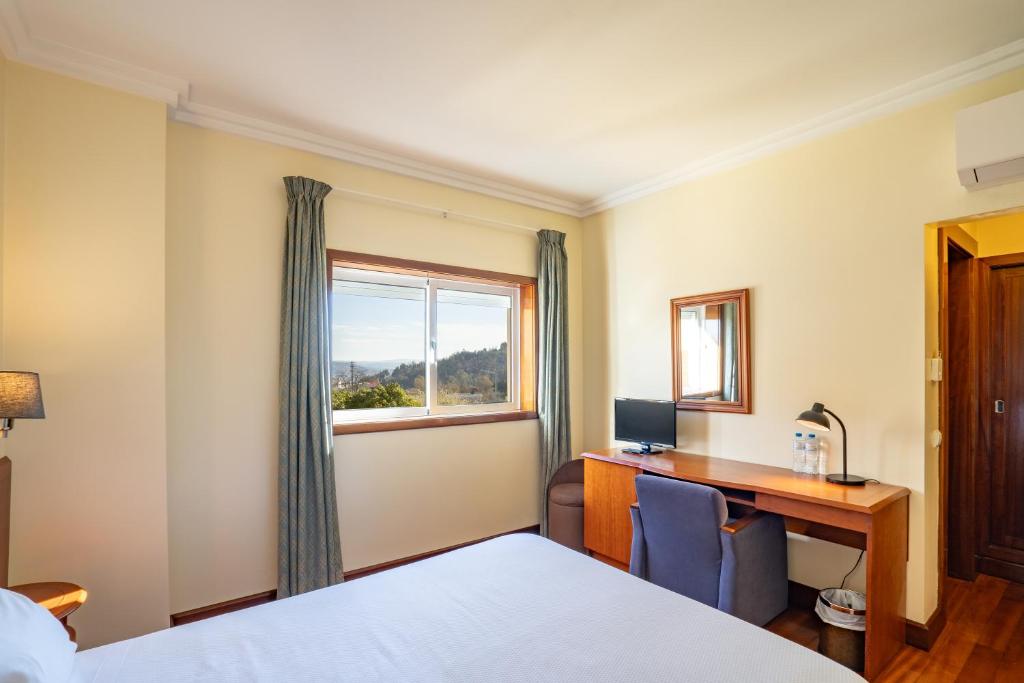 a hotel room with a desk and a window at Hotel Ulveira in Oliveira de Frades