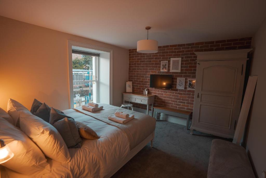 a bedroom with a large bed with a brick wall at The Jodrell Luxury Suites in Whaley Bridge