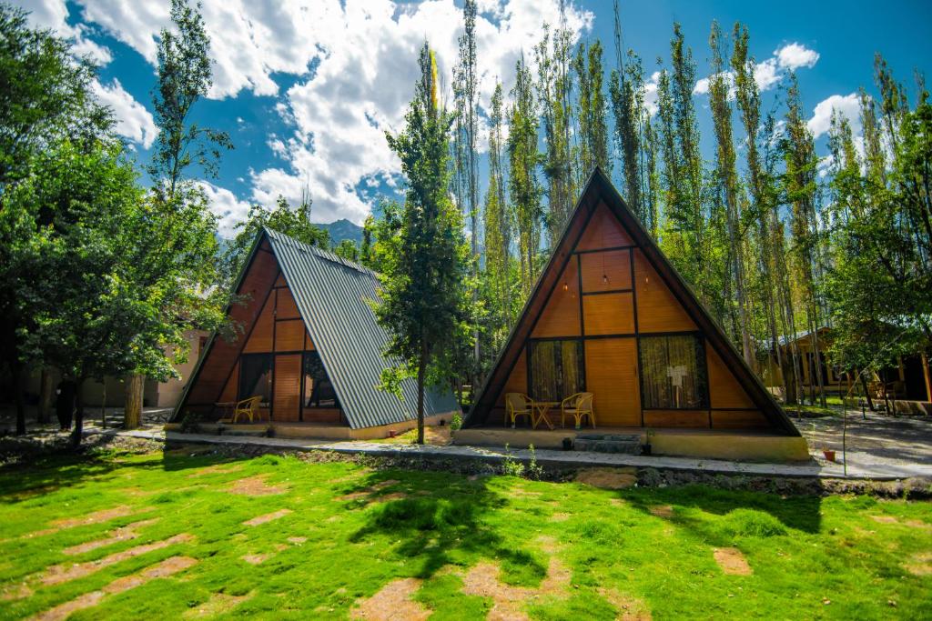 a frame cabin in the woods with grass and trees at Maple Resorts in Skardu