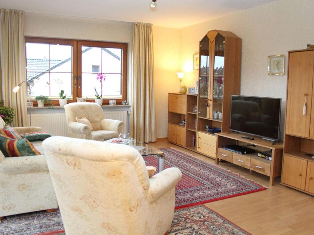 uma sala de estar com duas cadeiras e uma televisão em Nice apartment in Daun-Waldkönigen 
