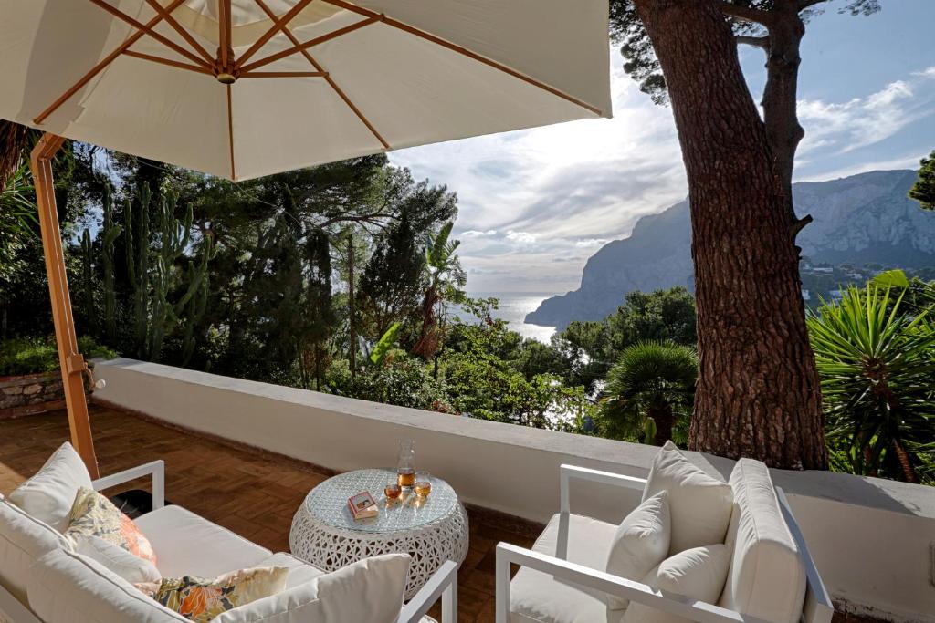 a patio with an umbrella and a table and chairs at Villa I Pini in Capri